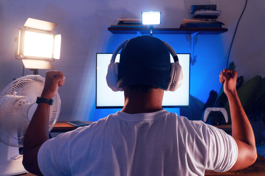 Latin man gaming online with headphones celebrating success