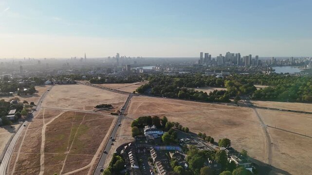 Climate change drought near Canary Wharf London aerial drone view of Greenwich Park with dry brown grass and city skyline UK heatwave Severe impact of a UK heatwave