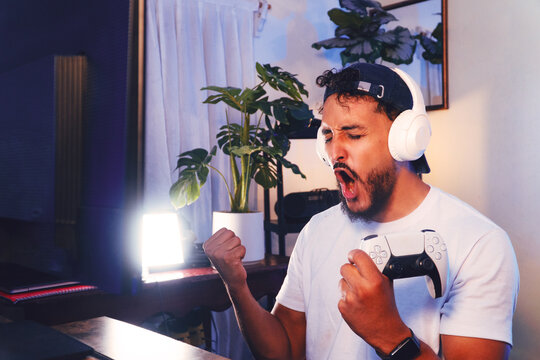Enthusiastic gamer celebrating victory holding game controller