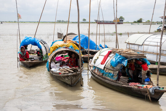 Munshiganj, Dhaka Division, Bangladesh - 14 August 2020: View of the nomadic Bedey community living on traditional wooden boats on the river with colorful tarps and household items.