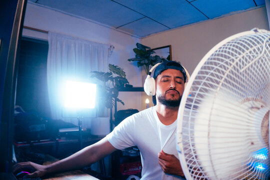 Man enjoying cool air from fan while gaming
