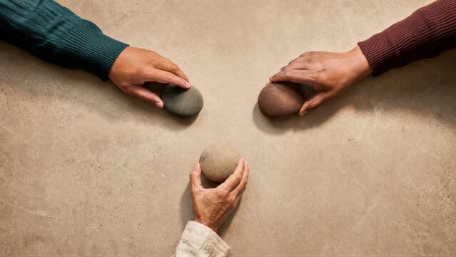 Three people hands touching smooth stones on table. Concept of teamwork, mediation, and conflict resolution.