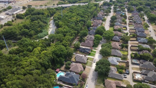 Established subdivisions border Ten Mile Creek greenbelt across southern Dallas suburbs. Swimming pools, shingle roofs, backyard patios, thick foliage reflect quiet community living, DeSoto, TX