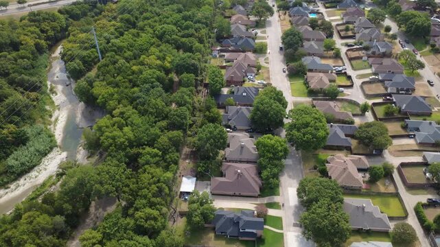 Paved residential lanes parallel Ten Mile Creek greenway in southern Dallas suburbs. Single-story brick homes, spacious lawns, private driveways demonstrate classic suburban charm, DeSoto, Texas