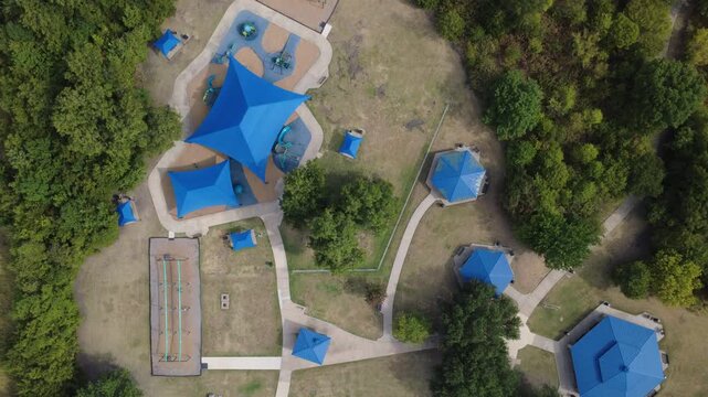 Blue canopy shades frame playground installations inside public playground park across metroplex. Curved walking trails, picnic gazebos, woodland boundaries demonstrate recreation, DeSoto, TX