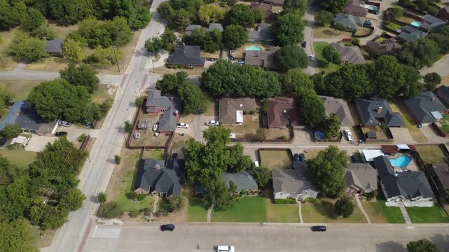 Residential subdivisions border mature oak foliage within Mesa Verde community in suburbs. Single story brick houses, expansive yards, paved streets show peaceful neighborhood living, DeSoto, TX