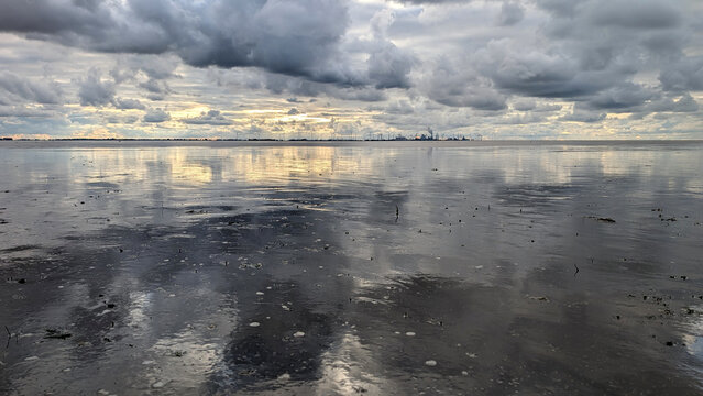Reflective tidal flats under storm clouds on the Wadden Sea, Germany. 