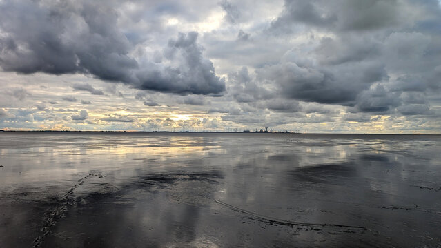 Reflective tidal flats under storm clouds on the Wadden Sea, Germany. 