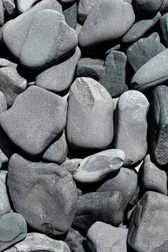 Sea pebble texture. Smooth beach stone pattern. Grey rock background macro. Coastal pebble stack layout. Monochrome stone surface. Natural gravel texture backdrop. Dark shadow rock detail. Ocean