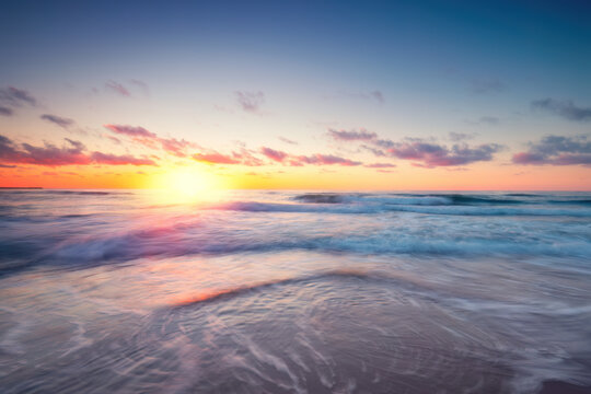 Sunriseon the beach with motion blur waves and colorful sky