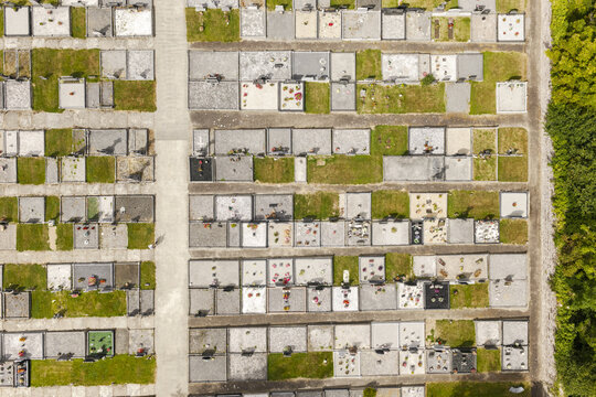 Aerial view of St Patrick's Church cemetery with orderly rows of graves, stone markers, and patches of green grass in Portlaw, County Waterford, Ireland.