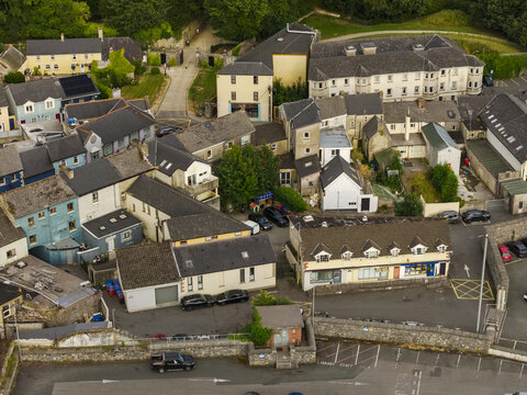 Aerial view of the town of Mallow with its mix of historic and modern buildings, rooftops, parking areas, and stone walls in Mallow, County Cork, Ireland.