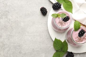 Naklejka premium Tasty blackberry smoothies with chia seeds, berries and leaves on light grey table, flat lay. Space for text
