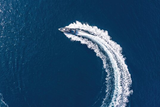 Speedboat cruising fast turning making white wake waves aerial view