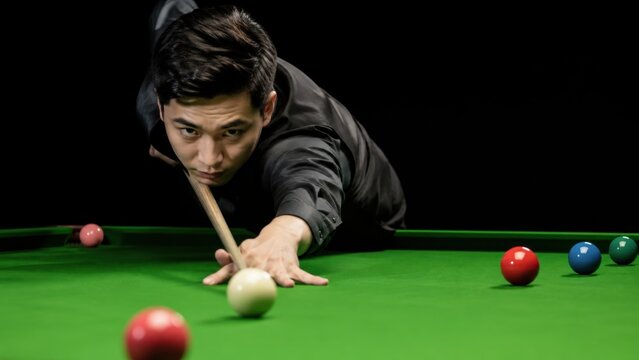 Focused Asian male snooker player taking precise shot aiming cue ball during professional billiards tournament match. Concept of action, pool table, cue sports. Copy space.