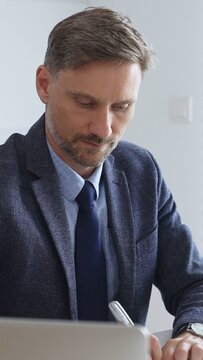 Focused businessman sitting at a modern desk, working intently on a laptop surrounded by folders, showcasing professionalism and determination. Audit and taxes in business
