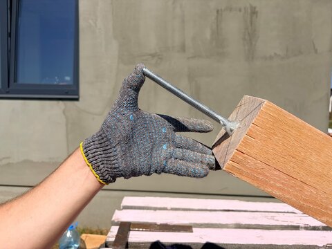 Manual building work. Construction worker inserting threaded metal rod with chemical anchor into wooden beam