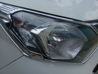 Close-up of a clean white car headlight with chrome trim accents, modern vehicle automotive detail. © BELL Art