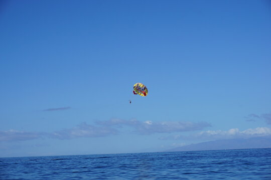 Parasail gliding above ocean under clear blue sky