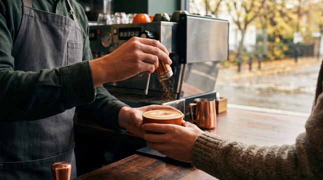 Barista preparing a pumpkin spice latte for a customer at a caf&eacute;  