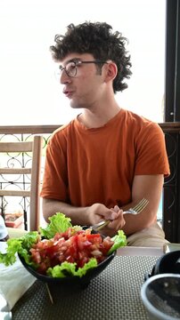 Marrakech, morocco. August 8, 2026. Caucasian young man with glasses eating a typical moroccan salad in a restaurant in marrakech. Slow motion video of a tourist on vacation