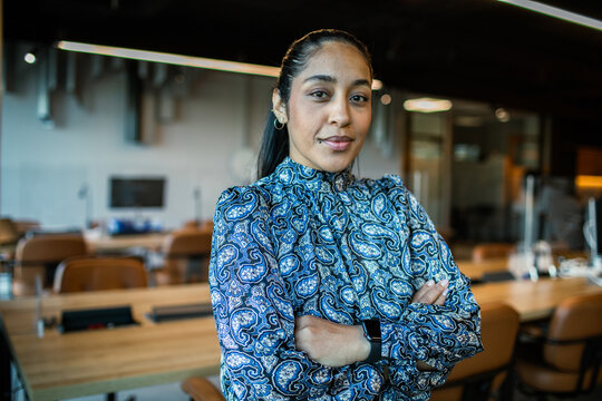 Confident businesswoman with crossed arms in modern office
