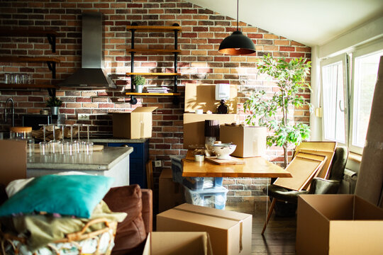 New homeowners moving boxes in sunny brick loft kitchen