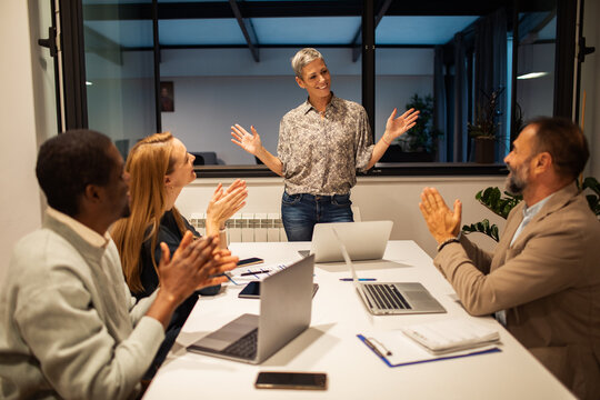 Team applauding female leader in modern office meeting