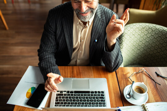 Smiling businessman using laptop at cafe table
