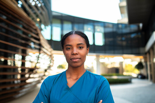 Confident nurse in blue scrubs outside hospital