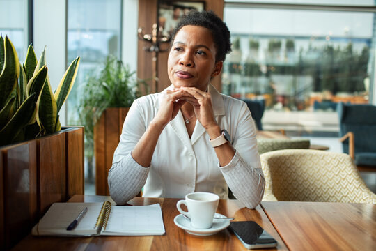 Thoughtful professional woman planning day at cafe with coffee