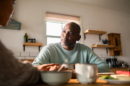Mature man comforting partner at home kitchen table