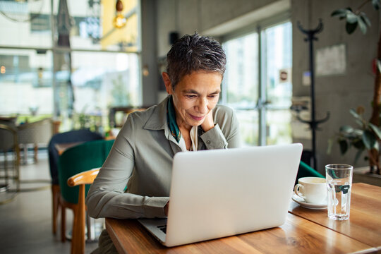 Senior woman working on laptop in cafe