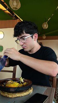 Marrakech, morocco. August 8, 2026. Young man with glasses enjoying a traditional moroccan tagine meal. He is sitting at a restaurant table, savoring the authentic cuisine