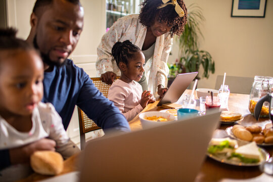Parents and children using devices at the breakfast table at home