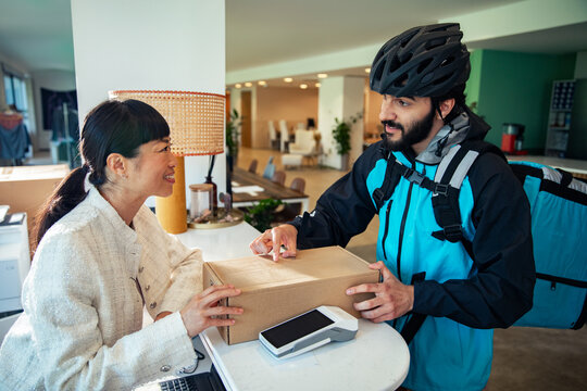 Bike courier delivering package to office receptionist at front desk