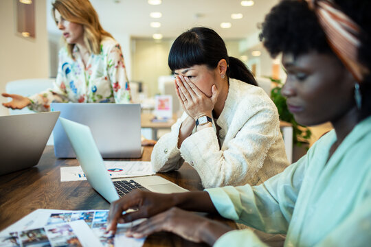 Stressed businesswoman with coworkers in modern office meeting