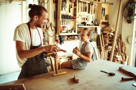 Father and daughter building wooden toy in workshop