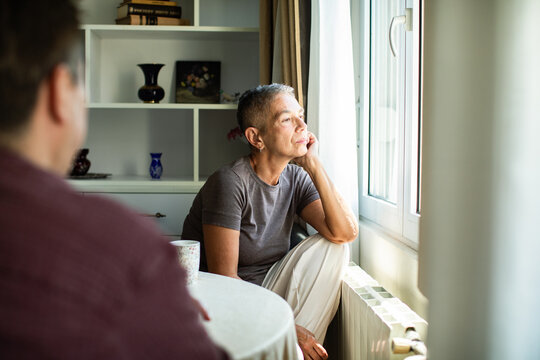 Older woman contemplating by window at home