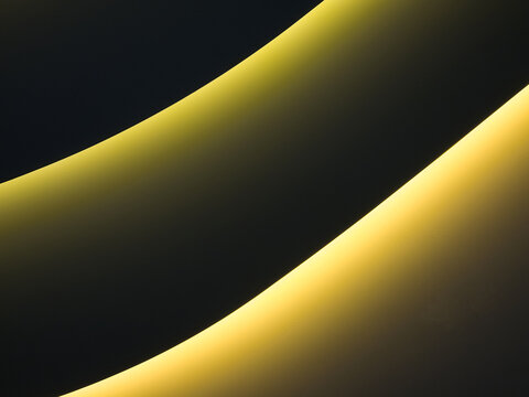 Abstract curved golden LED ambient lights on dark architectural ceiling background