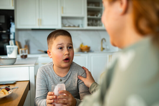 Mother comforting upset child at kitchen table