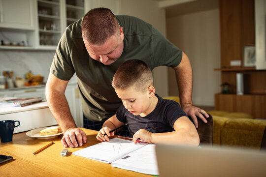Father helping son with homework at kitchen table