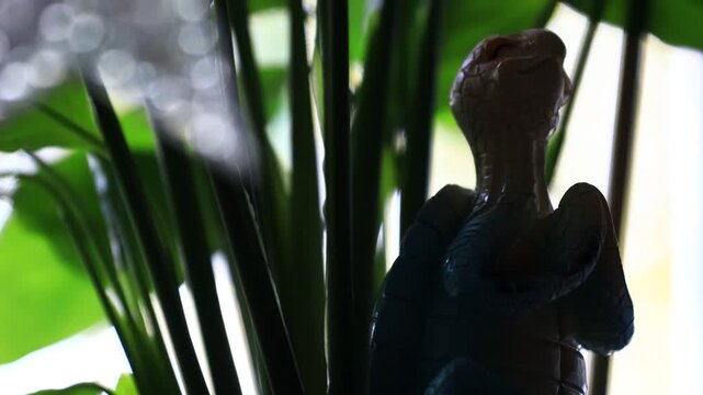 A figurine of an standing in front of a potted plant, perfect for a home decor or office setting