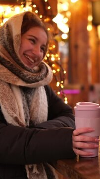 Girls Sweetly Converse, Drinking Hot Holiday Wine At The Bright Christmas Fair In Garland Light, Vertical Video