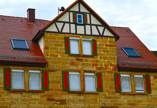 Historisches Sandsteinhaus mit Fachwerkgiebel und rot-gr&uuml;nen Fensterl&auml;den in Neuenstadt am Kocher, Baden-W&uuml;rttemberg, Deutschland