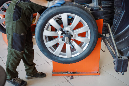 Wheel balancing service with mechanic spinning alloy wheel on balancing machine, automotive maintenance for smooth driving, vibration reduction, tire safety and repair.