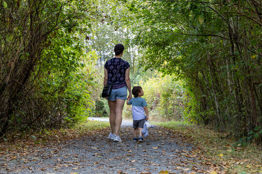 Mother and Young Son Walking Hand in Hand Through Lush Trail at Great Blue Heron Nature Reserve