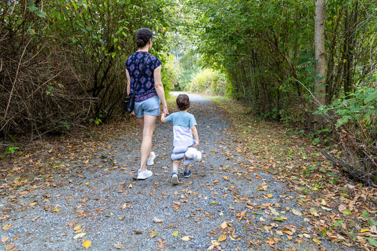 Mother And Son Walking Hand In Hand On Forest Trail At Great Blue Heron Nature Reserve, Chilliwack BC