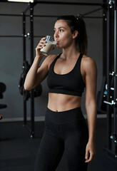 Fototapeta premium Fitness and healthy lifestyle, woman drinking protein shake after workout in a modern gym for muscle recovery
