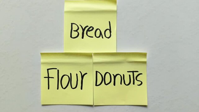 Three yellow sticky notes with handwritten words bread flour donuts isolated on white background